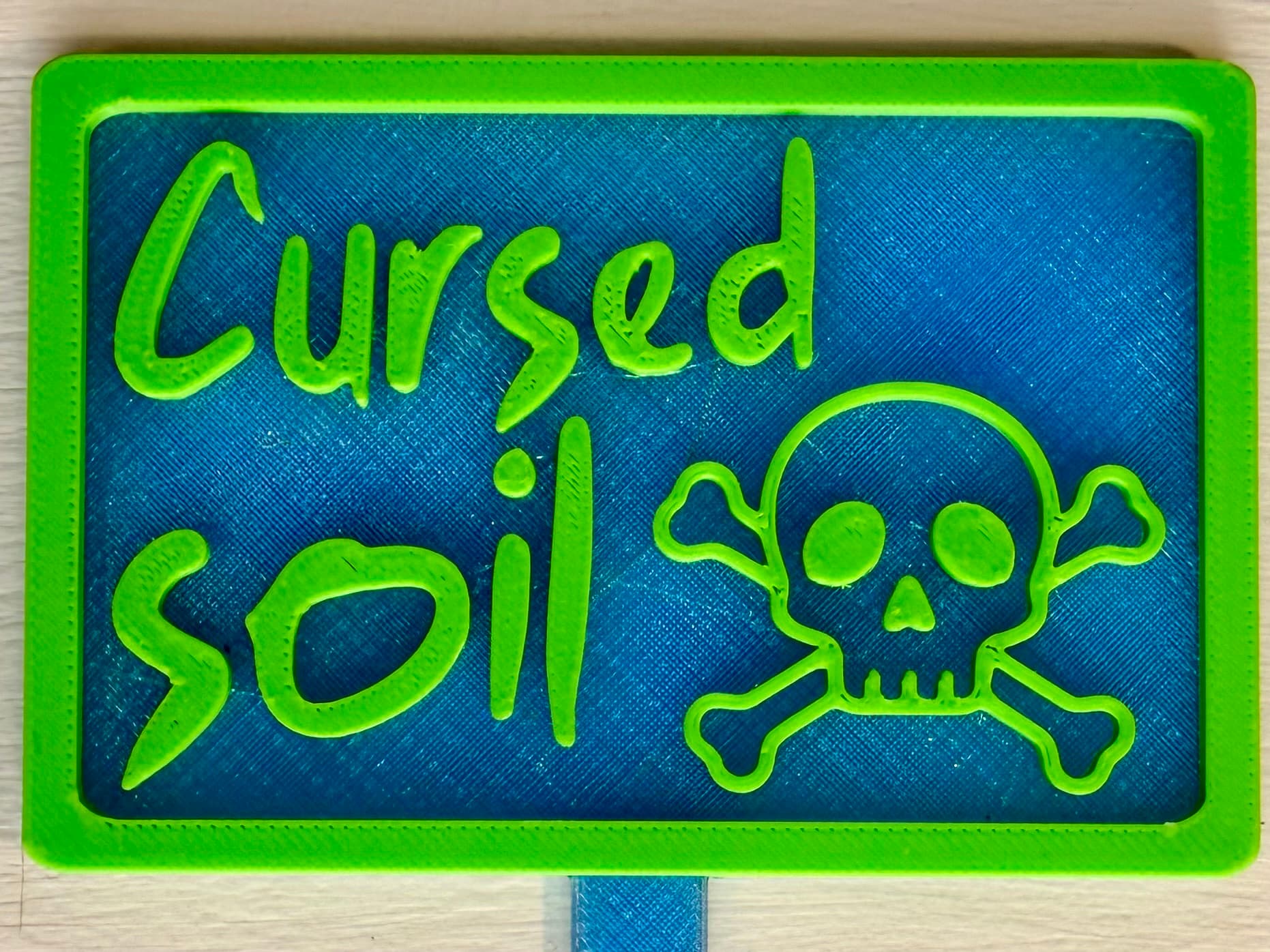 3D-printed pot pick with raised text reading 'Cursed Soil'