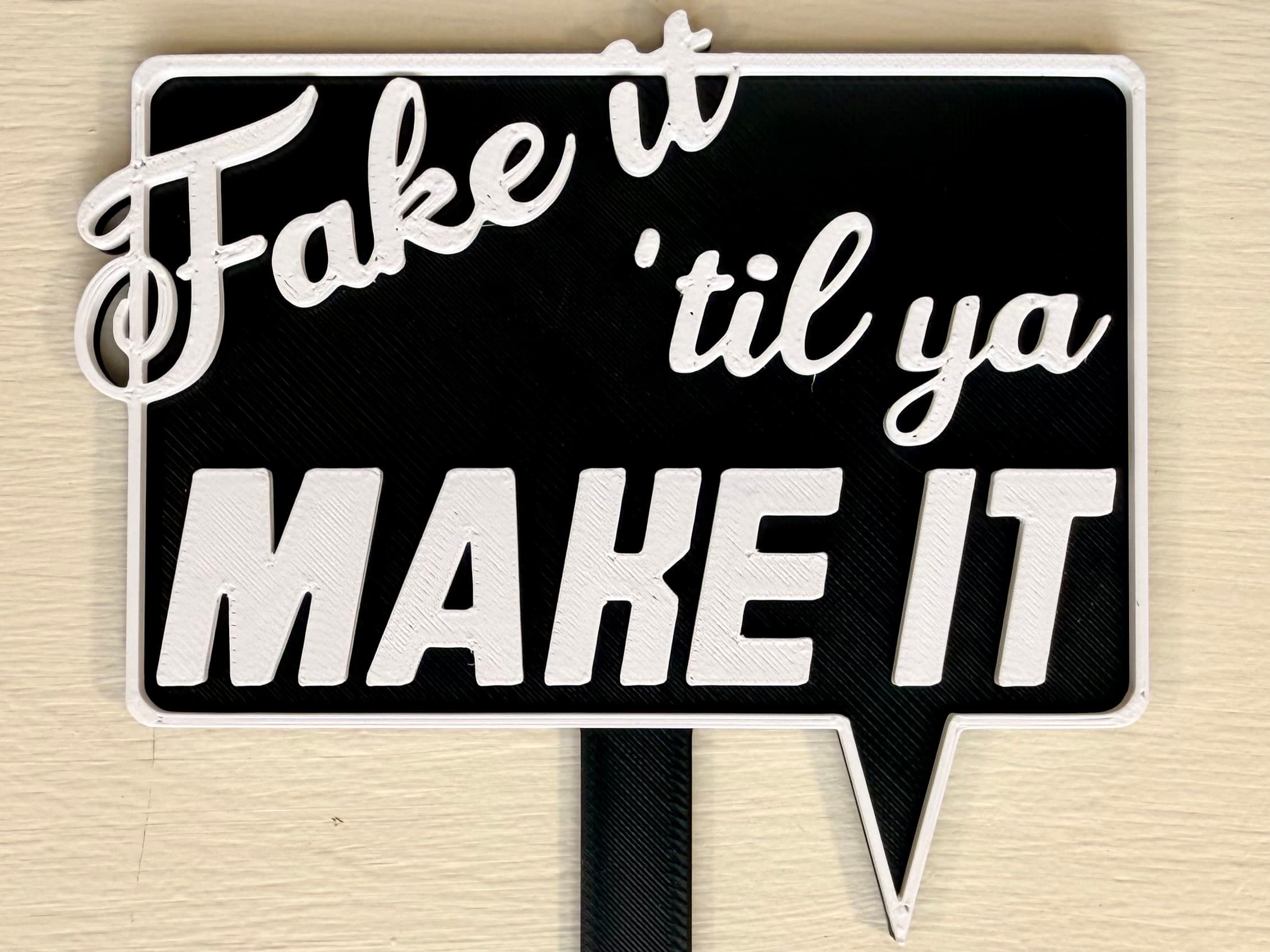 3D-printed pot pick with raised text reading 'Fake It Til You Make It'
