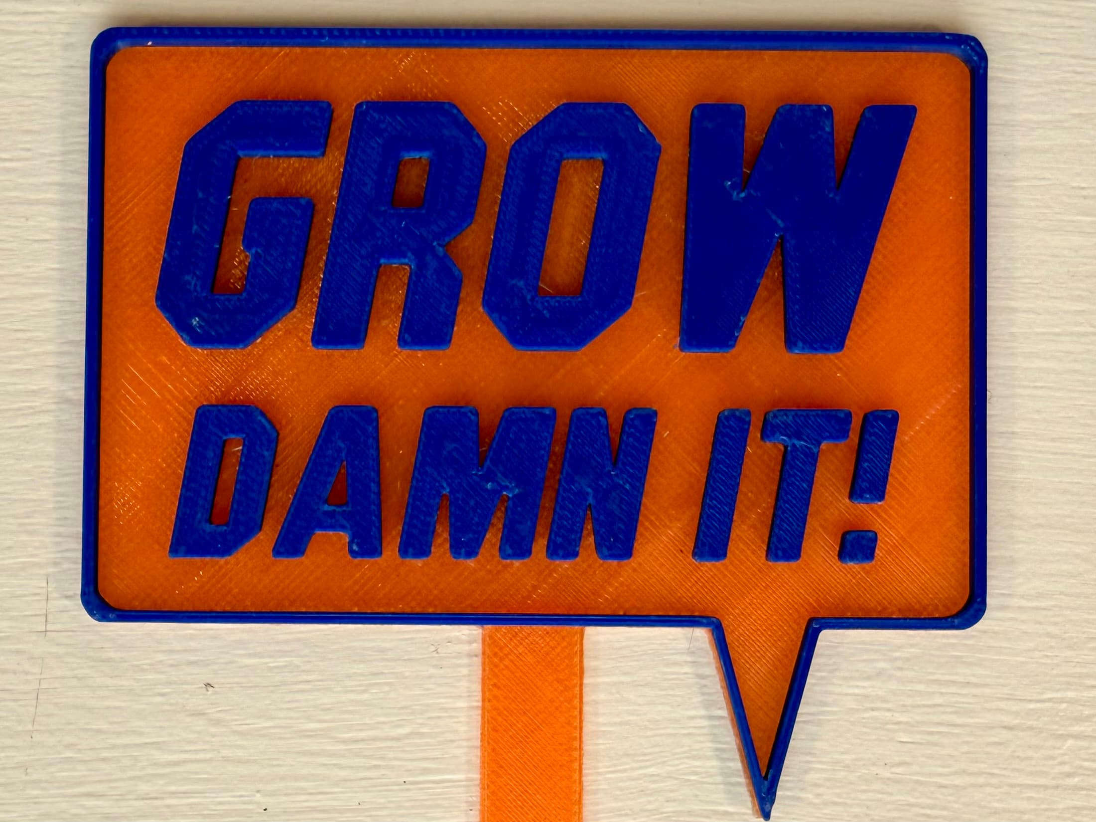 3D-printed pot pick with raised text reading 'Grow Damn It!'
