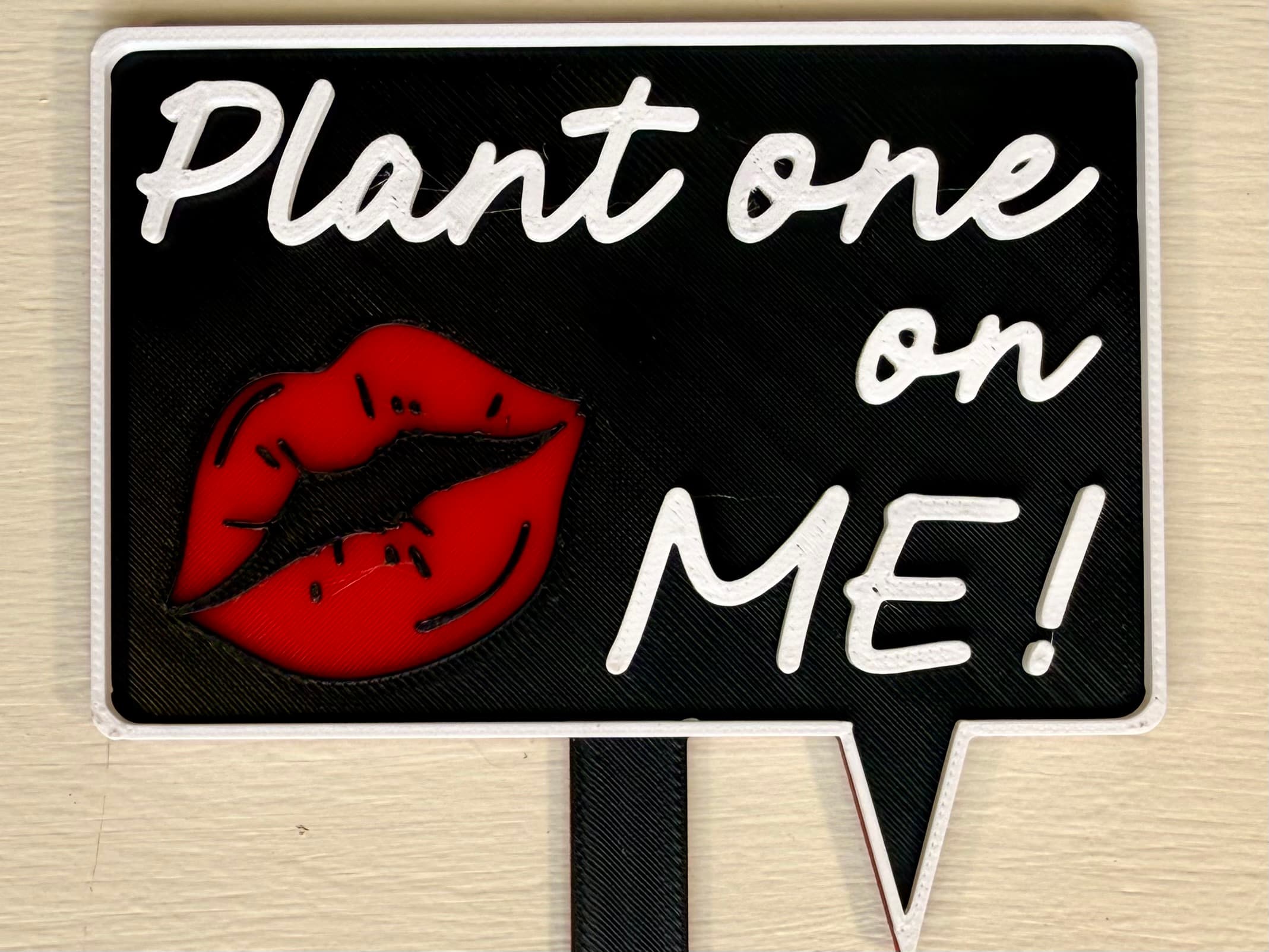 3D-printed pot pick with raised text reading 'Plant One on Me'