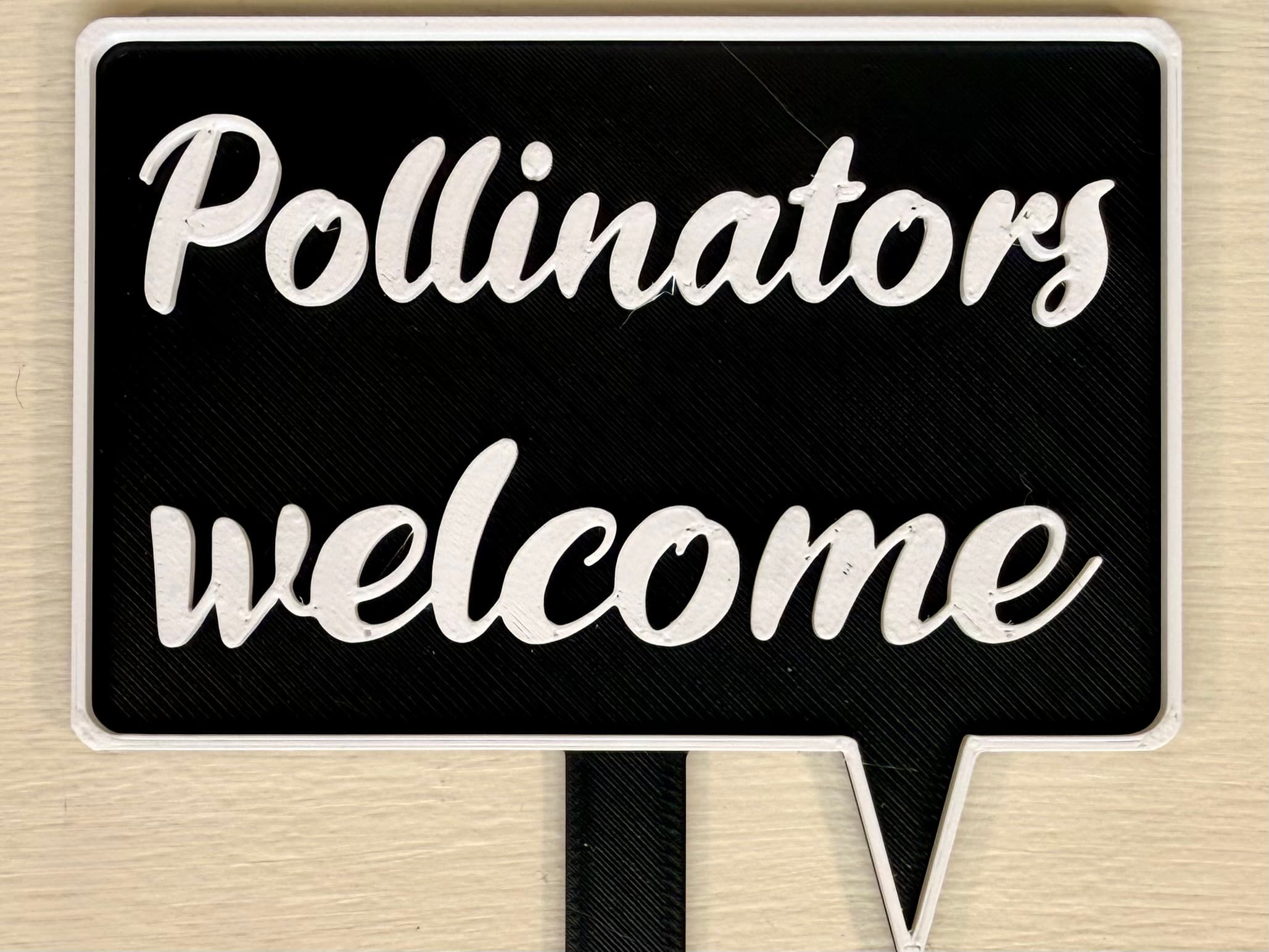 3D-printed pot pick with raised text reading 'Pollinators Welcome!'