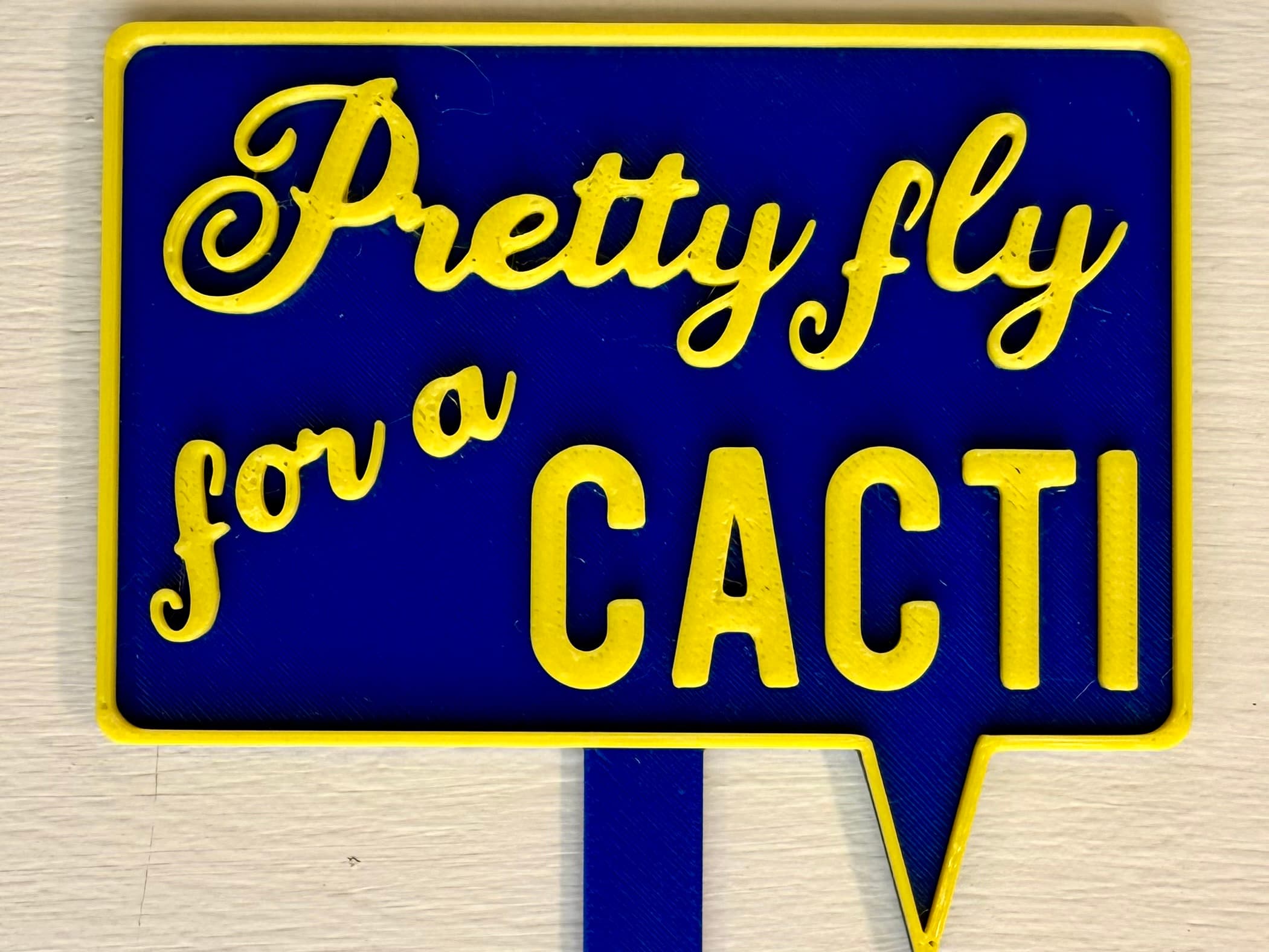 3D-printed pot pick with raised text reading 'Pretty Fly for a Cacti'