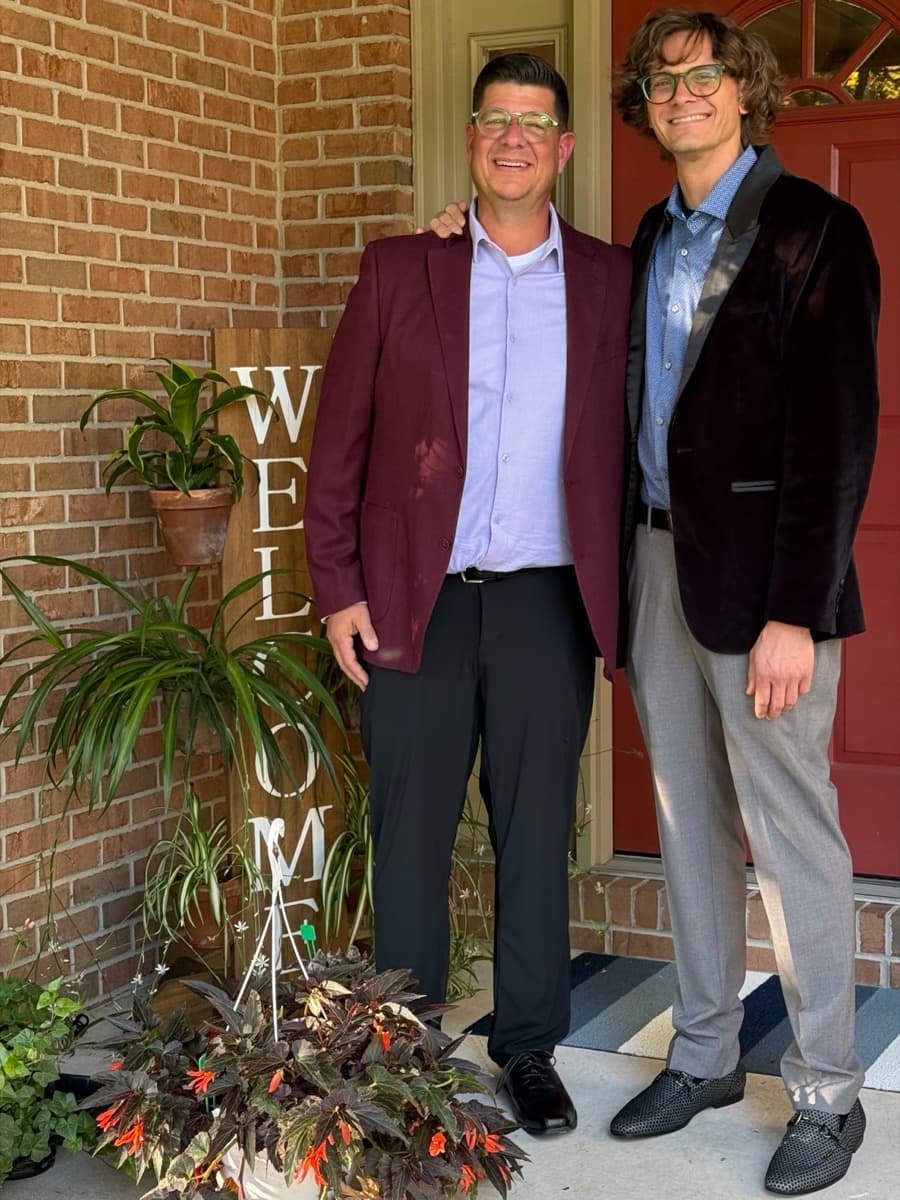 Will and Tim, co-founders of The Pot Slot, standing together on a front porch with potted plants and a welcome sign